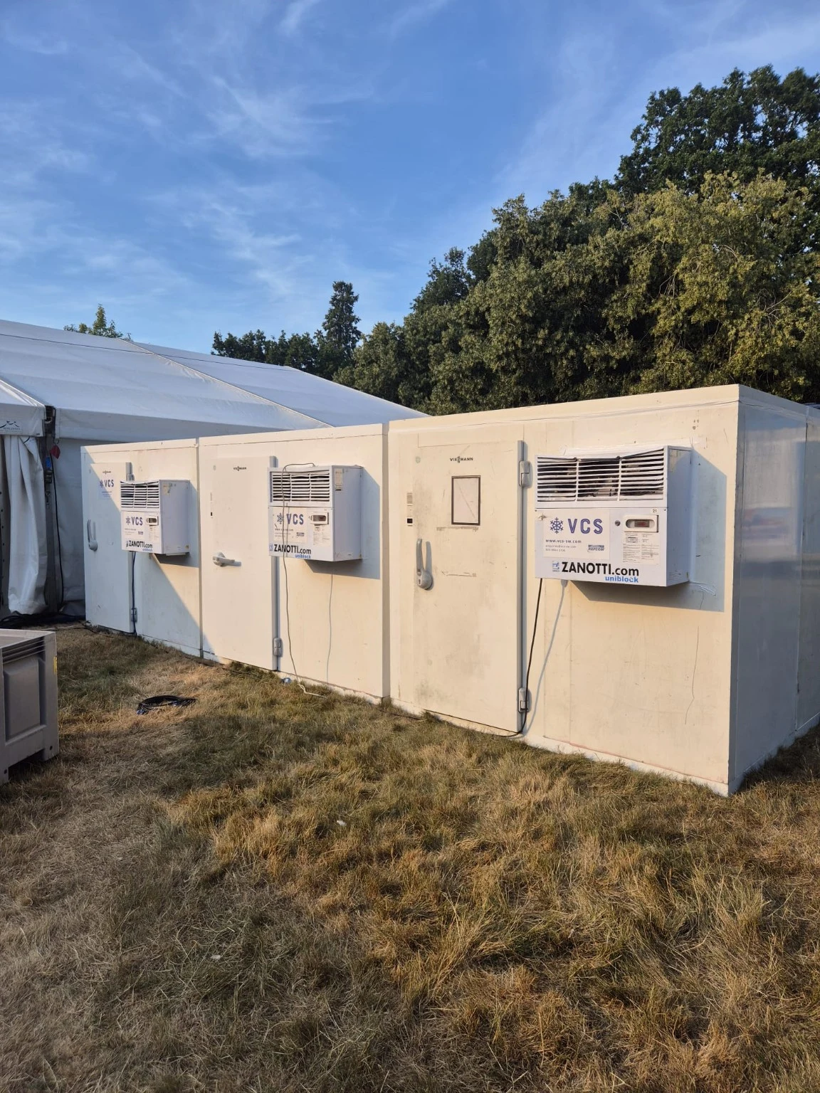 Two VCS fridges and one freezer arranged in a line next to the catering tent